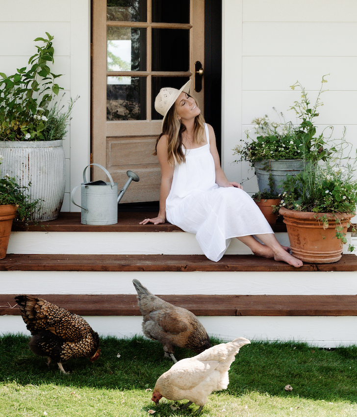 Photo of Chloe Mackintosh Founder of Boxwood Avenue outside in a white sundress on ranch.